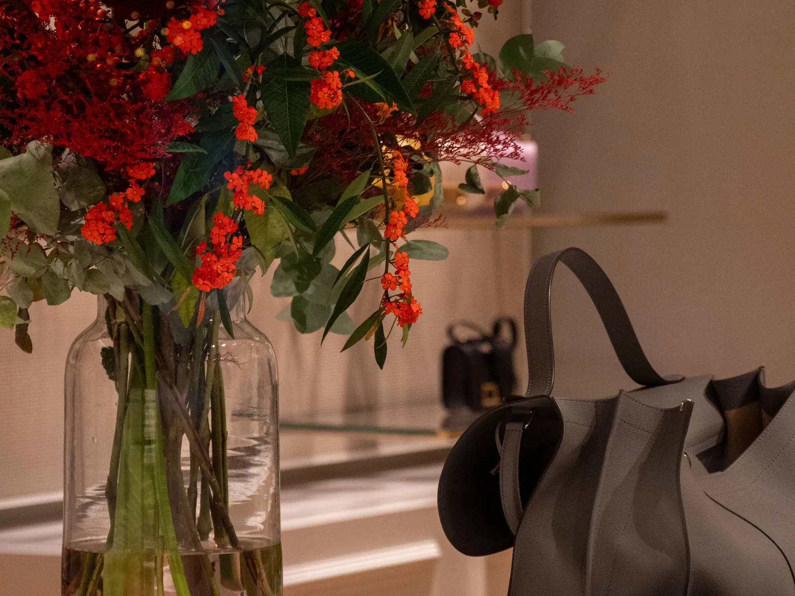 Flowers and a leather bag on a marble counter in a boutique