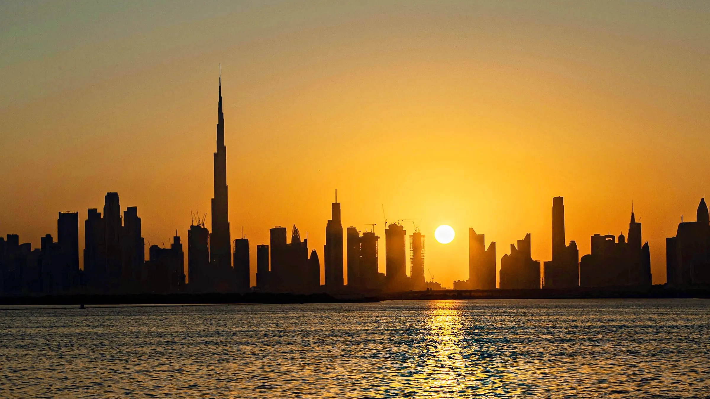 Dubai skyline with the Burj Khalifa at sunset over the water